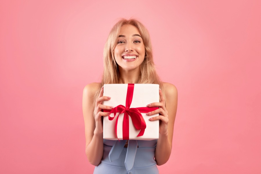 Woman holding a white gift box finished with a red ribbon