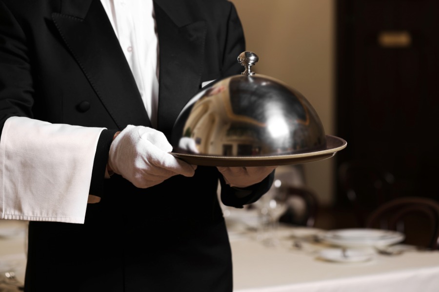 Catering staff wearing white service gloves before a formal banquet