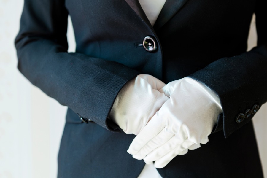 Hospitality staff in white gloves greeting guests at a formal event